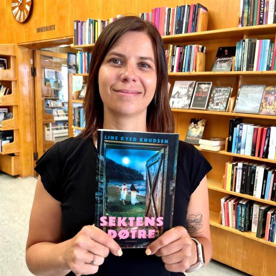 Bibliotekar Marianne Wismar Mühring står med bogen "Sektens døtre".