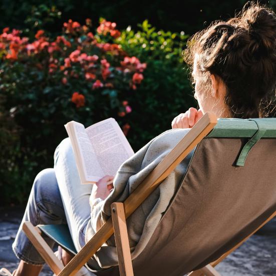 Kvinde sidder og læser i liggestol.