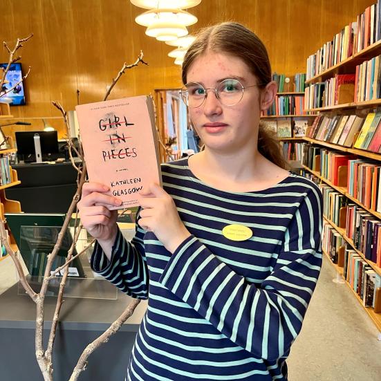 Praktikant Thea står med bogen "Girl in pieces"