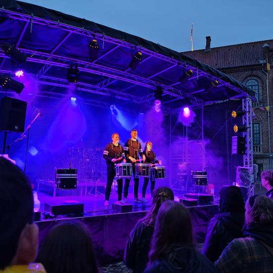 Billede fra Nyborg Kulturnat 2025, hvor Nordic Performers optræder på scenen på Torvet med blåt lys ved tusmørke.