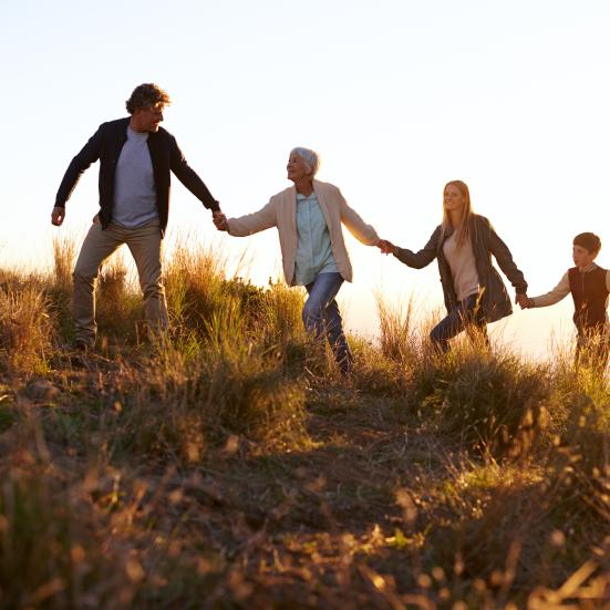 En familie i flere generationer vandrer op af en bakke hånd i hånd.
