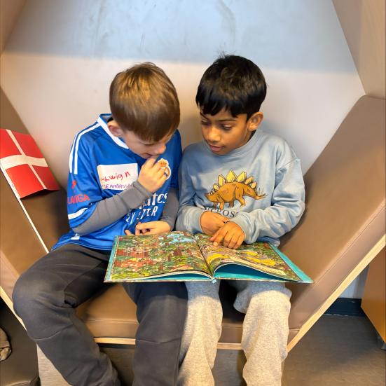 To drenge sidder og læser i bog sammen på Danehofskolens SFO-bibliotek