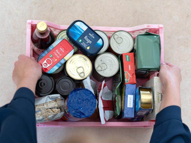 To hænder holder en kasse med forskellige konservesvarer til en krisesituation.
