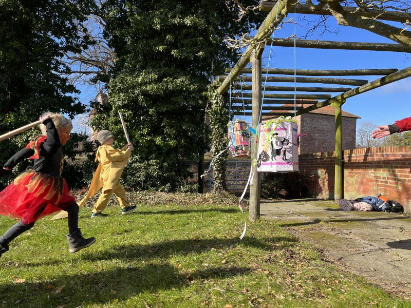 Udklædte børn løber mod fastelavnstønder med hævede køller.