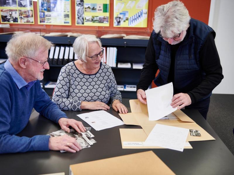 Frivillige fra lokalhistoriske arkiv viser billeder frem.