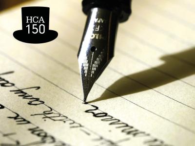 Pen skriver på papir. HCA-logo med sort høj hat med teksten HCA 150.