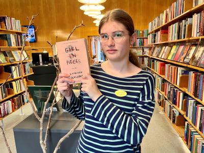 Praktikant Thea står med bogen "Girl in pieces"