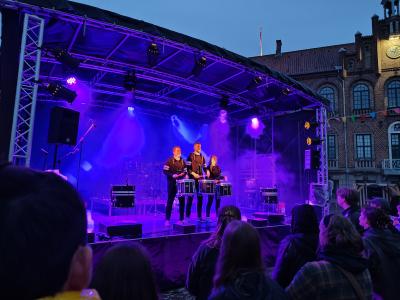 Billede fra Nyborg Kulturnat 2025, hvor Nordic Performers optræder på scenen på Torvet med blåt lys ved tusmørke.