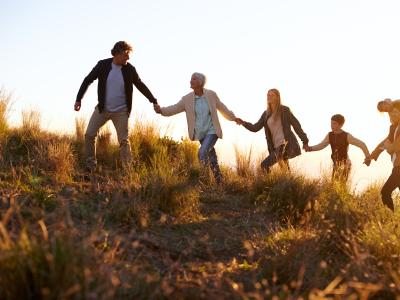 En familie i flere generationer vandrer op af en bakke hånd i hånd.