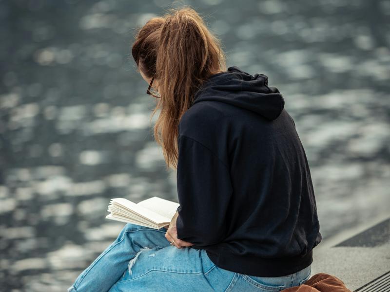 Kvinder sidder ved vandet og læser.