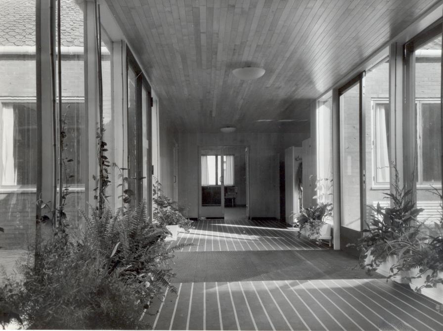 Glasgangen der binder hovedindgangen, haven og de to fløje sammen.