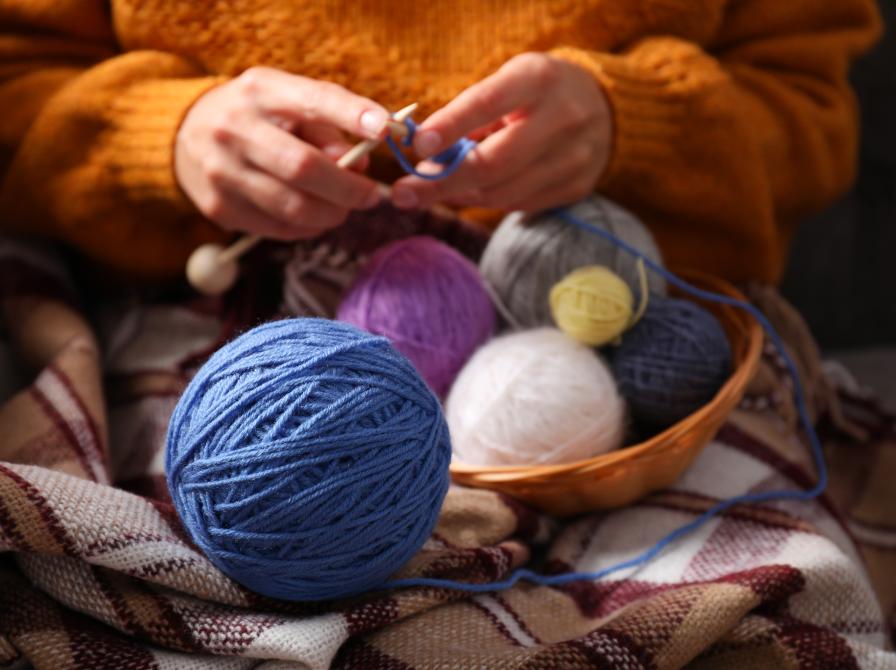 Garnnøgler og hænder der strikker.