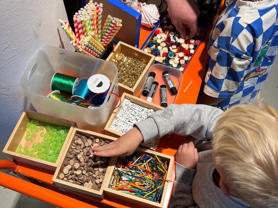 Børn står og vælger materialer til deres kæphest.