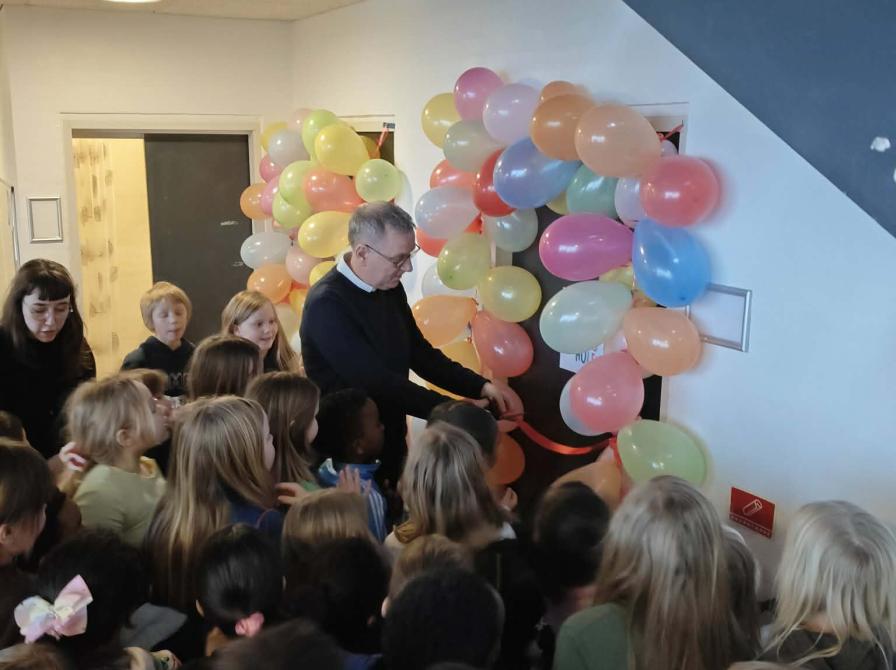 Skoleleder Lars Busk Svendsen klipper det røde bånd til Birkhovedskolens nye SFO-bibliotek "Boghulen".