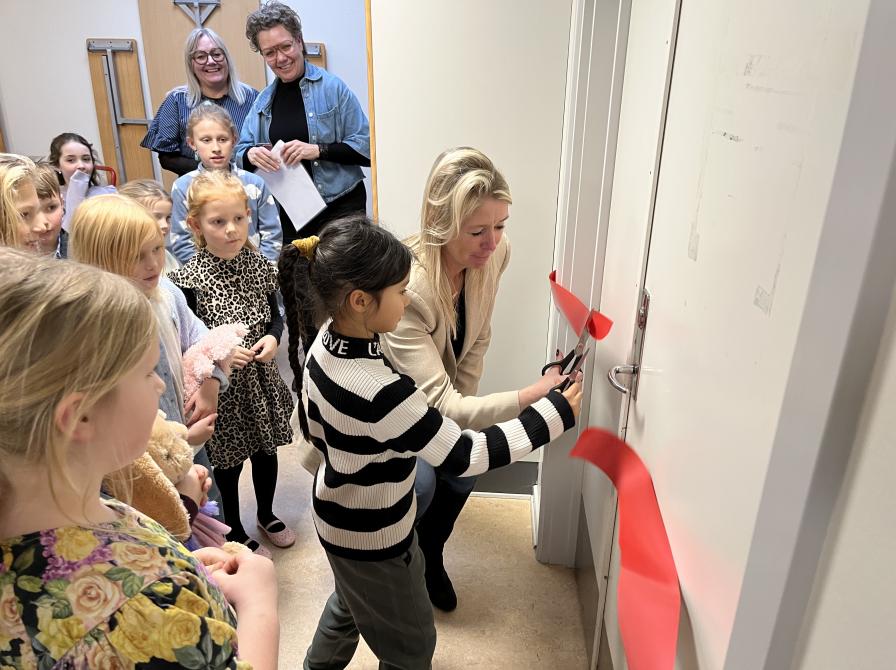 Maja fra 2. klasse og skoleleder Stine Terjesen klipper det røde bånd til Vibeskolens nye SFO-bibliotek.
