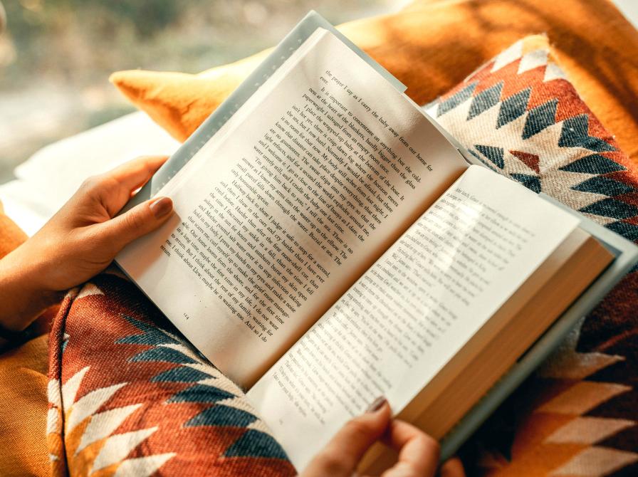 Billede til Read Hour. To hænder holder en opslået roman, der hvilker i skødet på læseren.